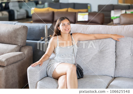 In furniture store,young girl is sitting on sofa with ottoman In furniture store,young girl is sitting on sofa with ottoman 106625548