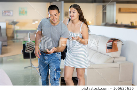 Smiling couple looking for new comfortable furniture in store 106625636