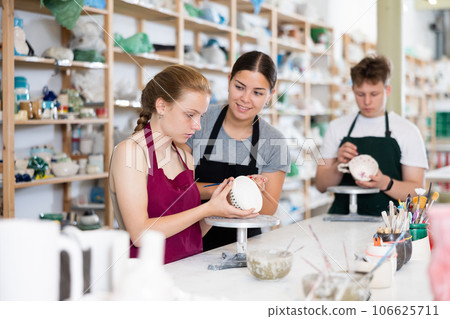 Master potter teaches teen girl how to draw and glaze pottery 106625711