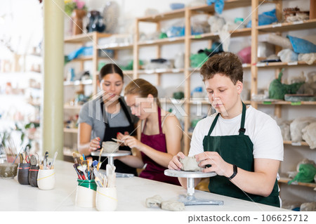 Teenager boy in apron modeling clay pottery in workshop 106625712