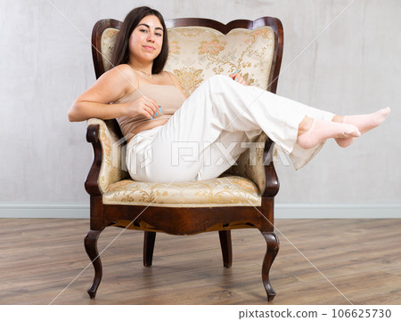 Young smiling woman posing on armchair in studio 106625730