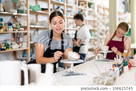 Young woman painting ceramic cup in ceramic workshop Young woman painting ceramic cup in ceramic workshop 106625745