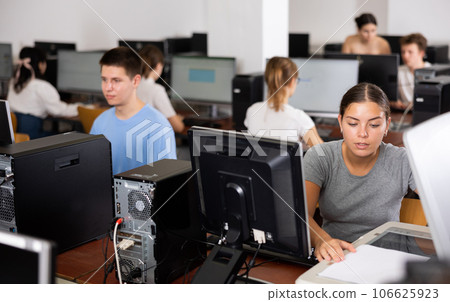 Smart female teenager learning computer science while she is using a PC in the computer classroom Smart female teenager learning computer science while she is using a PC in the computer classroom 106625923