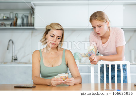 Teenage girl asking for pocket money from mother counting received salary Teenage girl asking for pocket money from mother counting received salary 106625936
