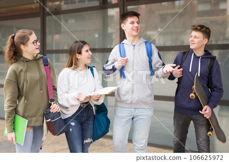 Four teenagers talking about play on walk in street 106625972