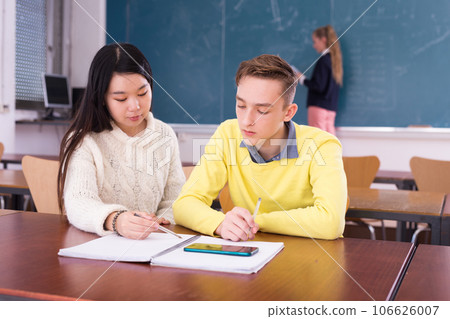Young guy and chinese girl students doing lesson in classroom Young guy and chinese girl students doing lesson in classroom 106626007