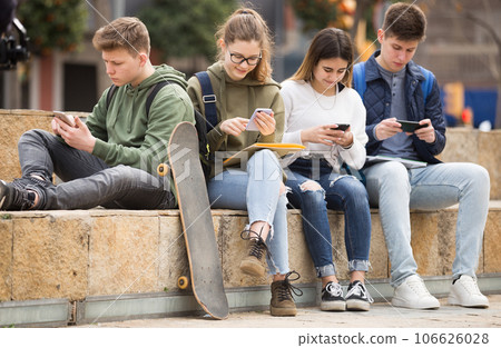 Group of teens using smartphones outdoors Group of teens using smartphones outdoors 106626028