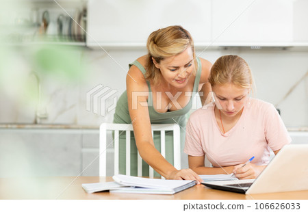 Teenage girl studying at home guided by friendly female tutor Teenage girl studying at home guided by friendly female tutor 106626033