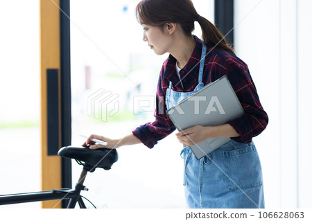 A female staff member repairing a bicycle A female staff member repairing a bicycle 106628063