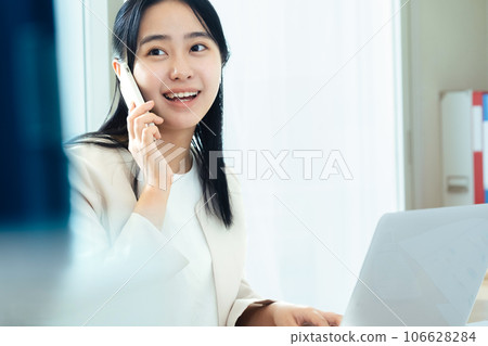 年輕女子在電腦前用智能手機交談 106628284