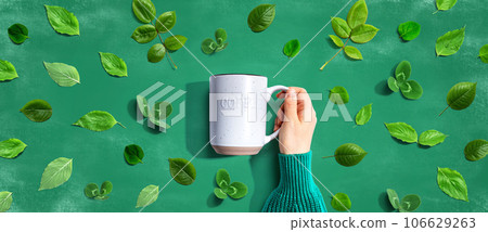 Person holding a mug with green leaves 106629263