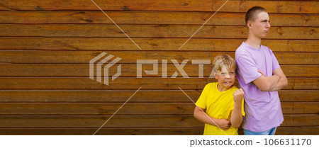 Brothers Conflicts. Offended brothers standing Back To Back Not Talking To Each Other, wooden wall with copy space. Rivalry concept 106631170