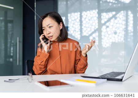 Upset and disappointed angry businesswoman talking on the phone, asian woman unhappy inside office at workplace with laptop. Upset and disappointed angry businesswoman talking on the phone, asian woman unhappy inside office at workplace with laptop. 106631641