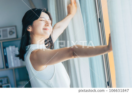 拉開窗簾沐浴在晨光中的女人 106631847