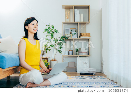 A woman watching a computer in a room 106631874