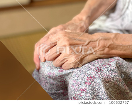 An elderly woman clasping her hands on her lap in front of her desk An elderly woman clasping her hands on her lap in front of her desk 106632767