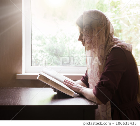 Girl reading a book by the window 106633433