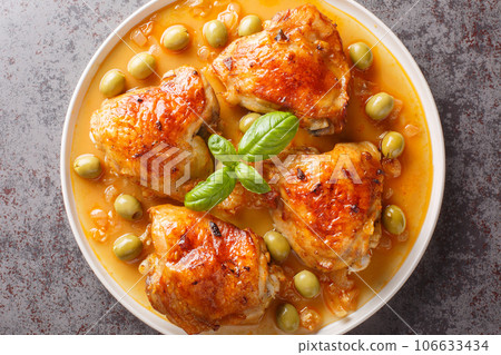 Fragrant hot ruddy chicken thighs baked with green olives close-up in a plate. Horizontal top view Fragrant hot ruddy chicken thighs baked with green olives close-up in a plate. Horizontal top view 106633434