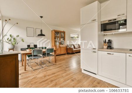 a kitchen and dining area in a modern home with white cabinets, wood flooring and an open door leading to the living room a kitchen and dining area in a modern home with white cabinets, wood flooring and an open door leading to the living room 106633781