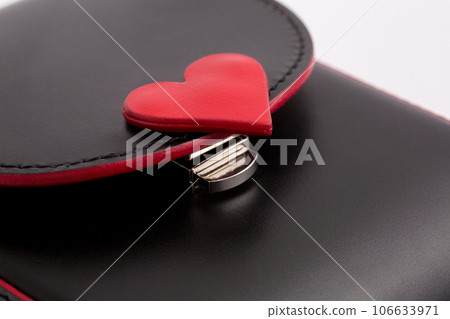 Small elegant black bag with red inserts in the shape of a heart and a silver chain on a white background Small elegant black bag with red inserts in the shape of a heart and a silver chain on a white background 106633971