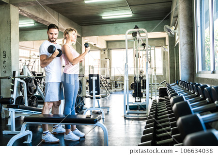 Man and woman working out with dumbbell in fitnes sport gym 106634038