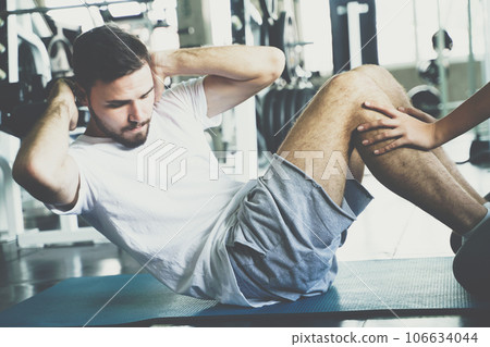 Sport man sit uplying on yoga mat exercise in gym 106634044