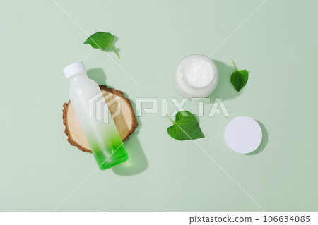 Top view of cosmetic bottle and jar mockup decorated with fish mint leaves and wooden podium on pastel background. Minimal concept for advertising. Using fish mint to treat acne is a safe and natural Top view of cosmetic bottle and jar mockup decorated with fish mint leaves and wooden podium on pastel background. Minimal concept for advertising. Using fish mint to treat acne is a safe and natural 106634085