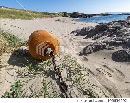 Orange buoy lying on the beach at low tide 106634392