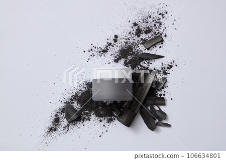 On the gray background, bamboo charcoal and powder decorated with a black jar without label for design. Bamboo charcoal extract helps fight acne-causing bacteria and remove scars. Advertising photo 106634801