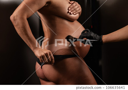 The master evens out an instant tan with a brush on the skin of a pregnant woman. Close-up of the tummy. The master evens out an instant tan with a brush on the skin of a pregnant woman. Close-up of the tummy. 106635641