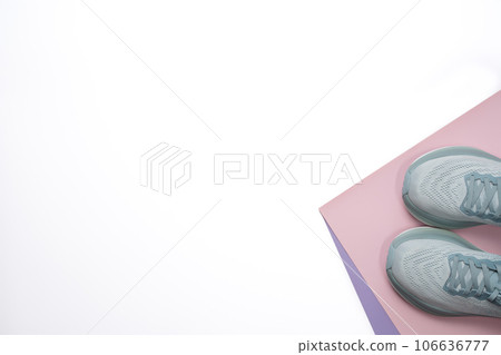 New light blue green female modern running shoe on pink purple and white geometrical background. Stylish monochrome shoes for active people that incorporate new health technology. Top view 106636777