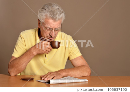 old man reading newspaper and drinking coffee 106637190