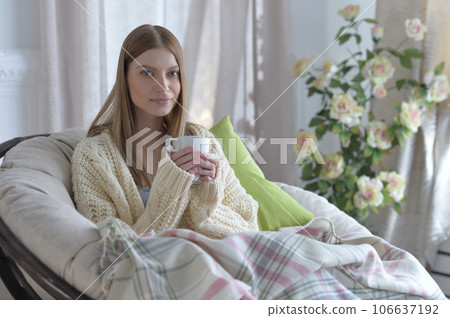 Portrait of young woman in pajamas on bed with fluffy plaid 106637192