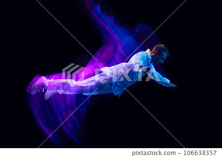 Freedom. Young guy in stylish clothes falling down against black studio background in neon with mixed lights effect. Levitation Freedom. Young guy in stylish clothes falling down against black studio background in neon with mixed lights effect. Levitation 106638357