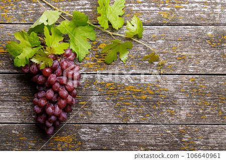 Grape with vine leaves on wooden table Grape with vine leaves on wooden table 106640961