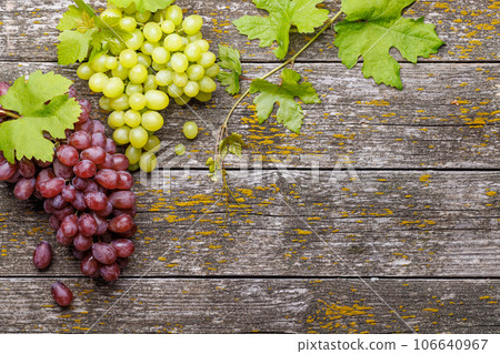 Grape with vine leaves on wooden table Grape with vine leaves on wooden table 106640967