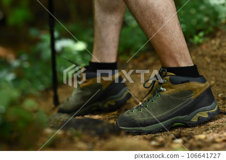 Male legs with hiker boots walking along the forest path. Traveling and adventure concept Male legs with hiker boots walking along the forest path. Traveling and adventure concept 106641727