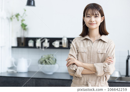 A woman in work clothes standing in the kitchen A woman in work clothes standing in the kitchen 106642259