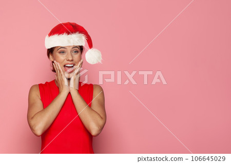 Happy shocked Christmas woman in Santa hat having fun on pink background Happy shocked Christmas woman in Santa hat having fun on pink background 106645029