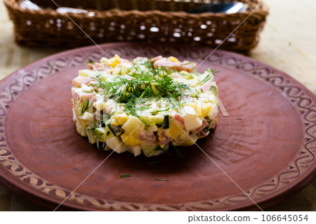 Traditional Russian salad with peas and mayonnaise, served in a cylinder on a clay plate Traditional Russian salad with peas and mayonnaise, served in a cylinder on a clay plate 106645054