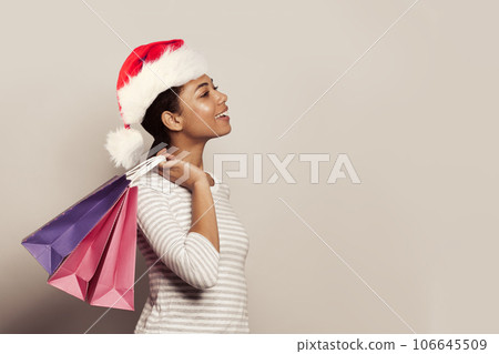 Christmas portrait of attractive woman in Santa hat holding shopping bags on white background 106645509
