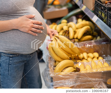 Pregnant woman buys bananas in the store.  106646167