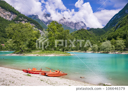 Amazing beautiful turquoise lake Tenno in Trentino region of Italy, surrouded by Alps mountains.  panoramic view with tiny island and canoe 106646379