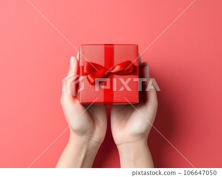 Illustration of woman's hands holding a red gift box with ribbon on a red background, top view, minimalist composition. AI generated 106647050