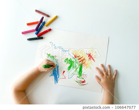 small child draws with pastel crayons on white table. small child draws with pastel crayons on white table. 106647077