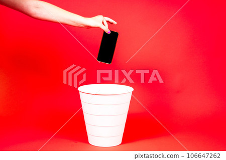 The smartphone is thrown into the trash for disposal and recycling 106647262
