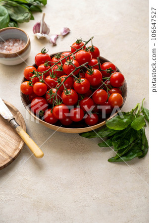 Fresh cherry tomatoes with basil and garlic in wooden bowl. Fresh cherry tomatoes with basil and garlic in wooden bowl. 106647527