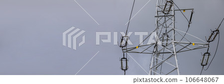 Against the background of an overcast sky stands a high-voltage electric pole. 106648067