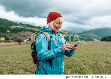 Woman holding phone in mountains, view from behind. Road trip, transport, travel, technology and people concept. High quality photo 106648179