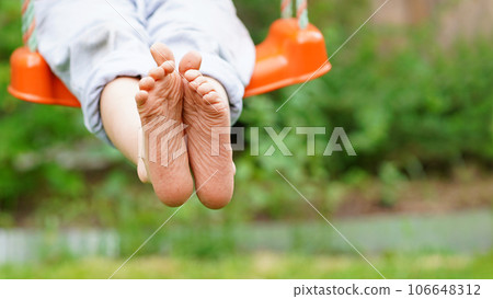 Closeup of happy kid sitting and swinging, sunny summer day, countryside background. Child feet barefoot. Copy space. Banner Closeup of happy kid sitting and swinging, sunny summer day, countryside background. Child feet barefoot. Copy space. Banner 106648312